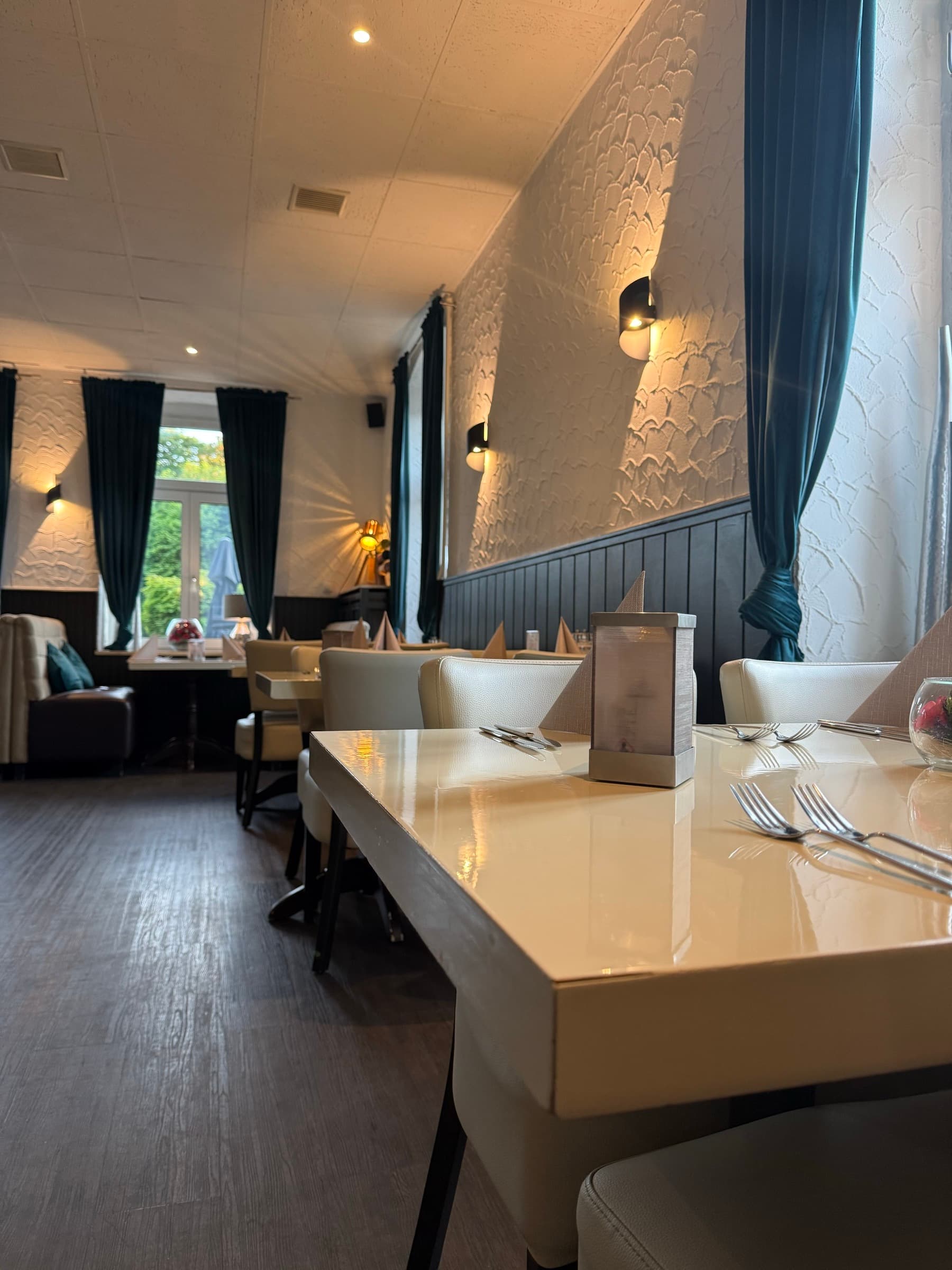Eingedeckter Tisch am Fenster im hellen Gastraum