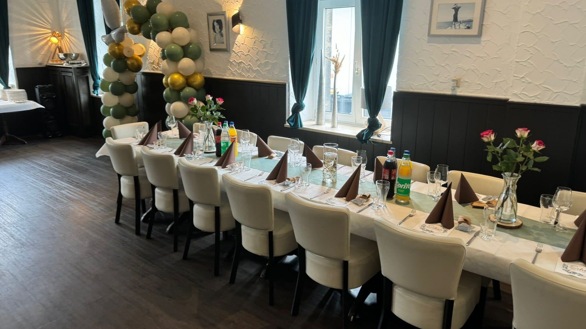Festlich gedeckte lange Tafel mit Ballonbogen, Rosen und Servietten für eine Familienfeier in der Taverne Mykonos